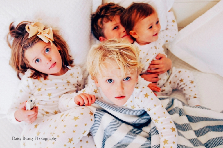 four blue eyed siblings on a bed in greenwich ct by daisy beatty photography